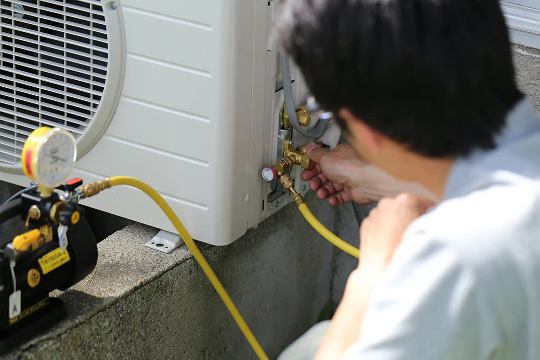 Technician connecting gauges to an outdoor mini-split unit